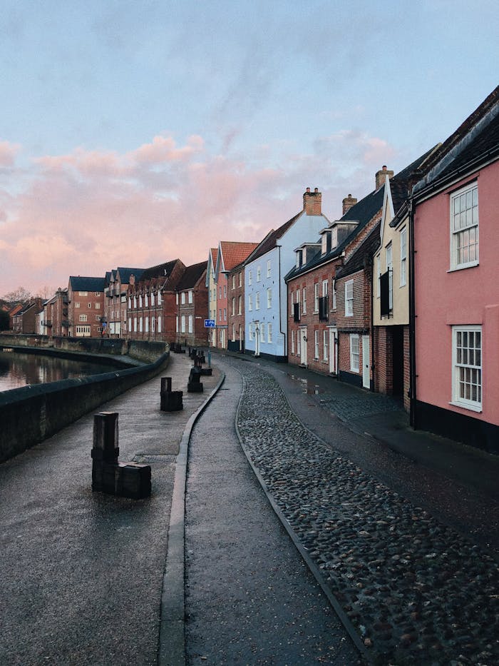 Beautiful cobblestone street in Norwich, England, showcasing colorful historic homes at dusk.